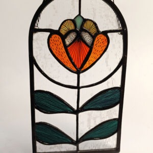 Vitrail Bijou de Fenêtre de style Art Nouveau, en forme d'arc en ogive. Le motif central est une fleur stylisée orange vif et vert émeraude sur un fond de verre texturé transparent.