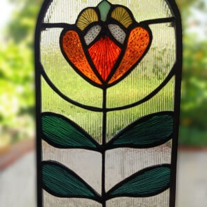 Vitrail Bijou de Fenêtre "Séraphine" : Fleur stylisée Art Nouveau en verre coloré. Pièce artisanale parfaite pour filtrer la lumière et décorer votre intérieur. dimensions 200 X 120 mm. Livré avec cordon pret à le suspendre devant une fenêtre.